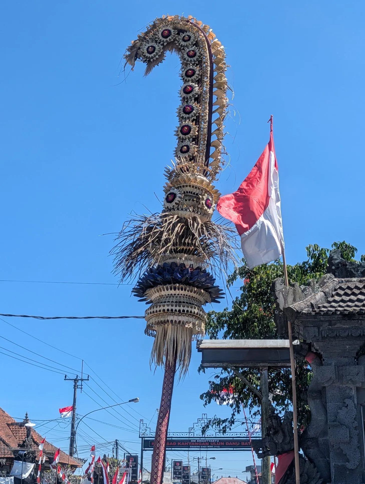 路边高耸的 penjor 竹饰与印尼国旗