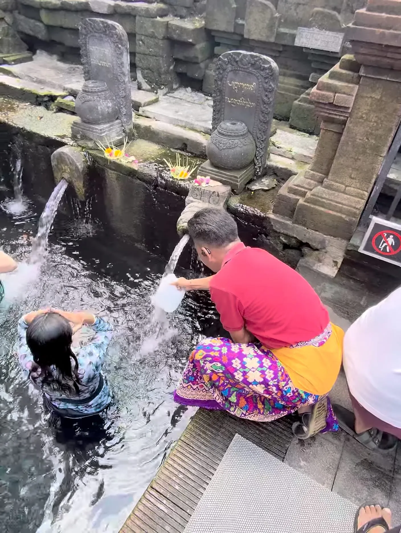 阿州在沐浴区用塑料桶接圣水
